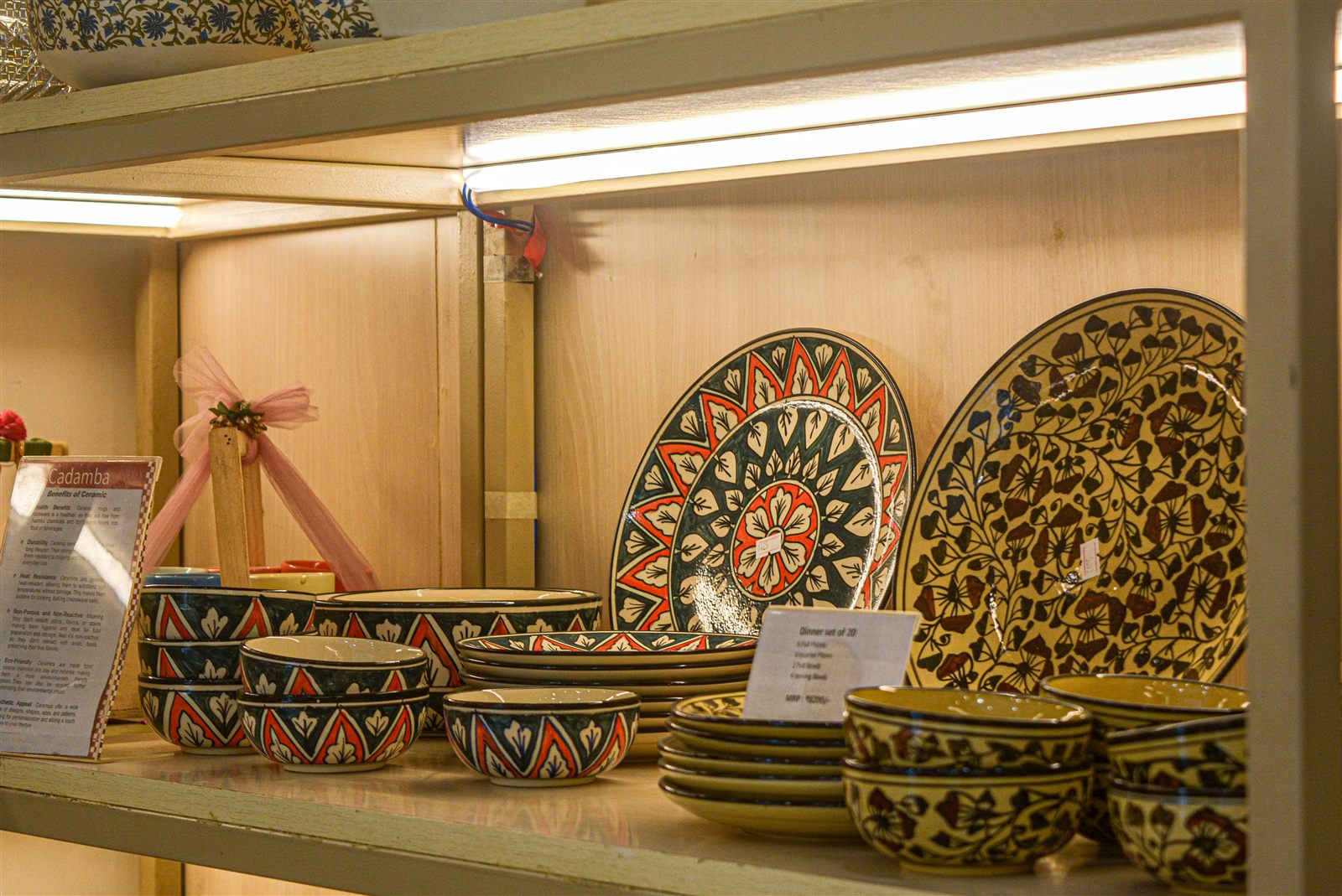 Plates and bowls displayed on a lit shelf at Cadamba